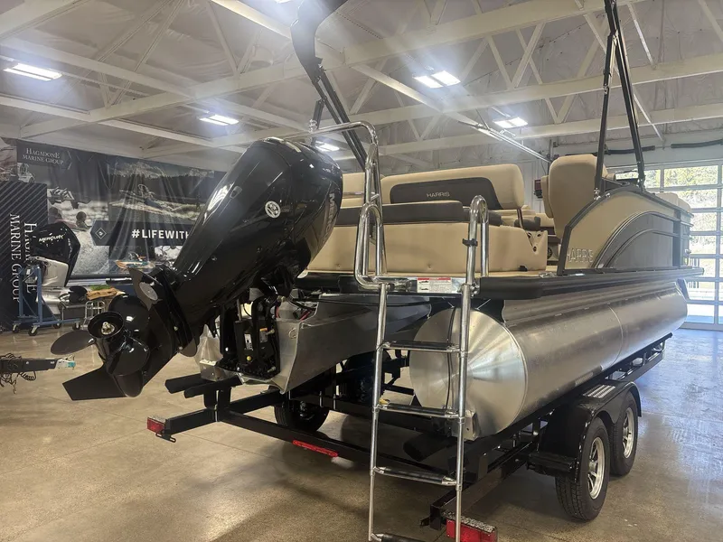 Slide: The Image of 2024 Harris Cruiser 210 pontoon boat with Mercury outboard motor in showroom. - 5