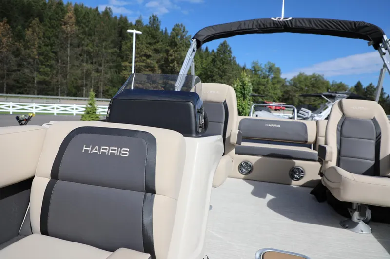 Slide: The Image of 2024 Harris Cruiser 230 boat interior with plush seating and scenic forest backdrop. - 16