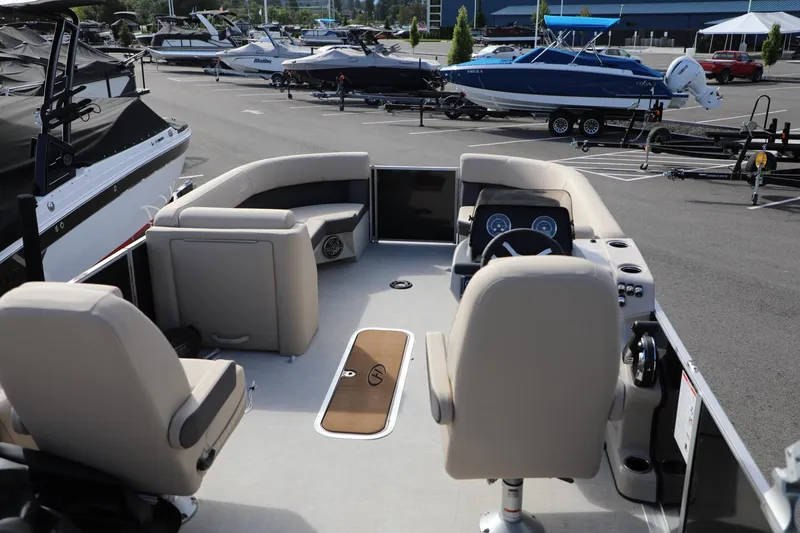 Slide: The Image of 2024 Harris Cruiser 230 boat interior with beige seating and steering console in a marina. - 18