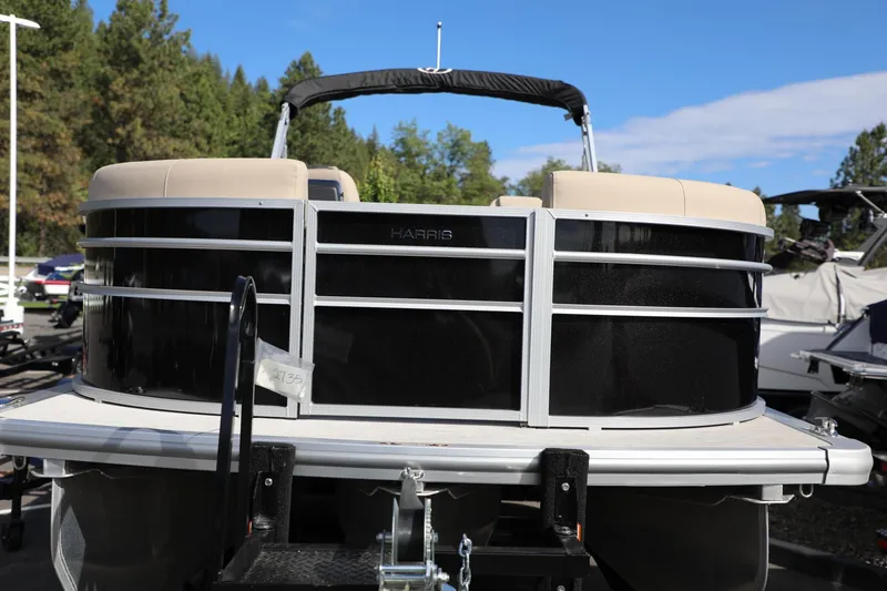 Slide: The Image of 2024 Harris Cruiser 230 pontoon boat with black exterior, parked outdoors. - 3