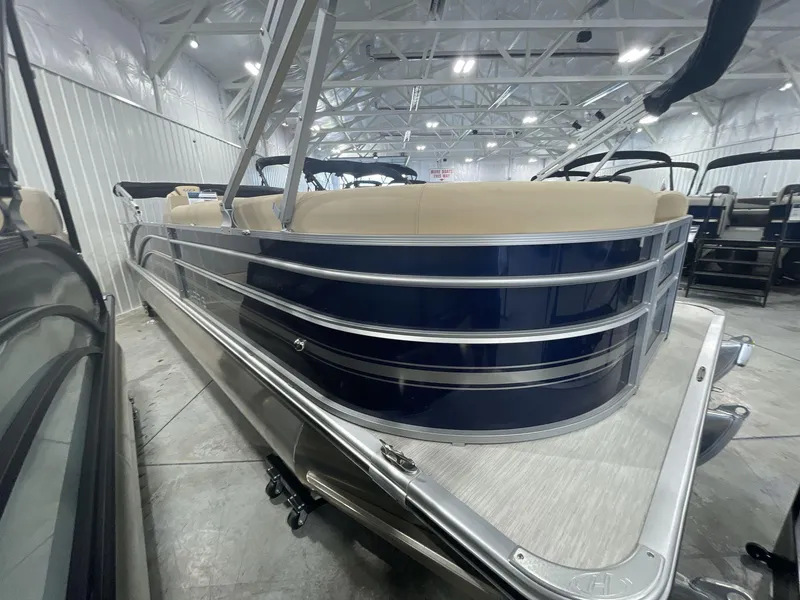 Slide: The Image of 2023 Harris Cruiser 250 pontoon boat in showroom, featuring sleek design and beige seating. - 4