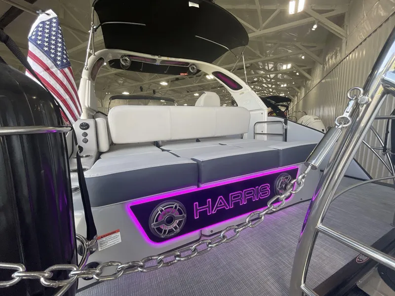 Slide: The Image of 2023 Harris Grand Mariner 250 boat with illuminated logo and American flag in a showroom. - 6