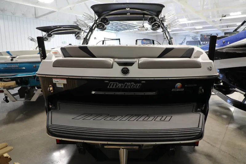 Slide: The Image of 2014 Malibu 24MXZ boat in showroom, rear view with sleek design and branding. - 18