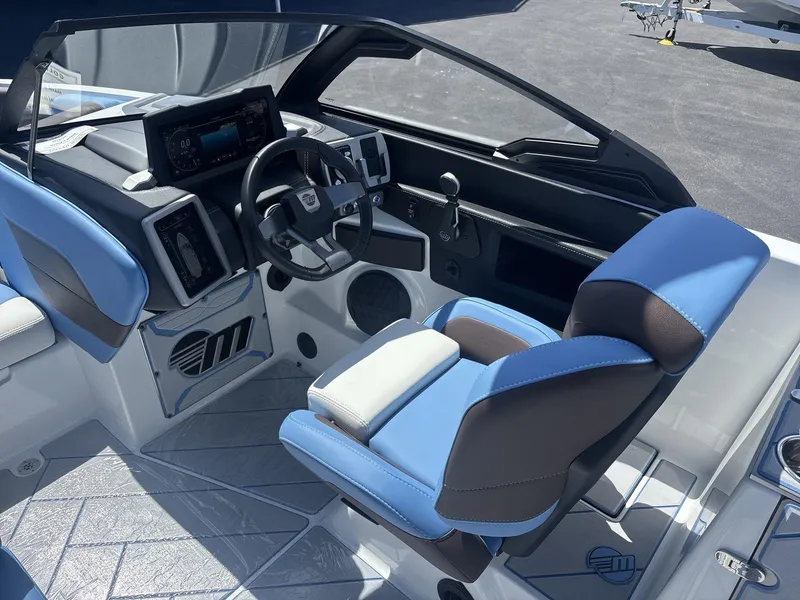 Slide: The Image of 2024 Malibu 25LSV boat interior with blue and white seating, modern dashboard, and steering wheel. - 10