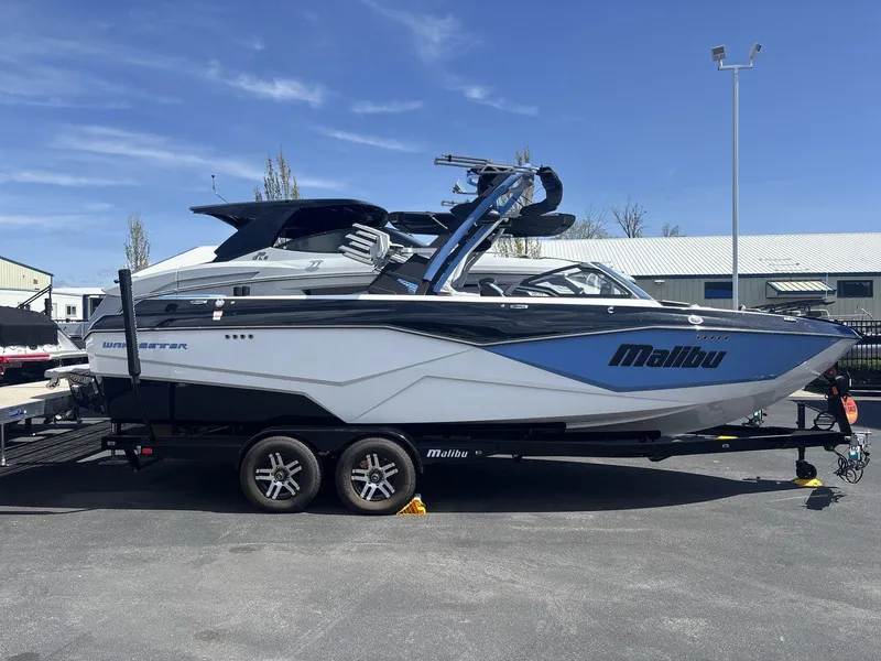 Slide: The Image of 2024 Malibu 25LSV boat on trailer, blue and white design, parked outdoors. - 3