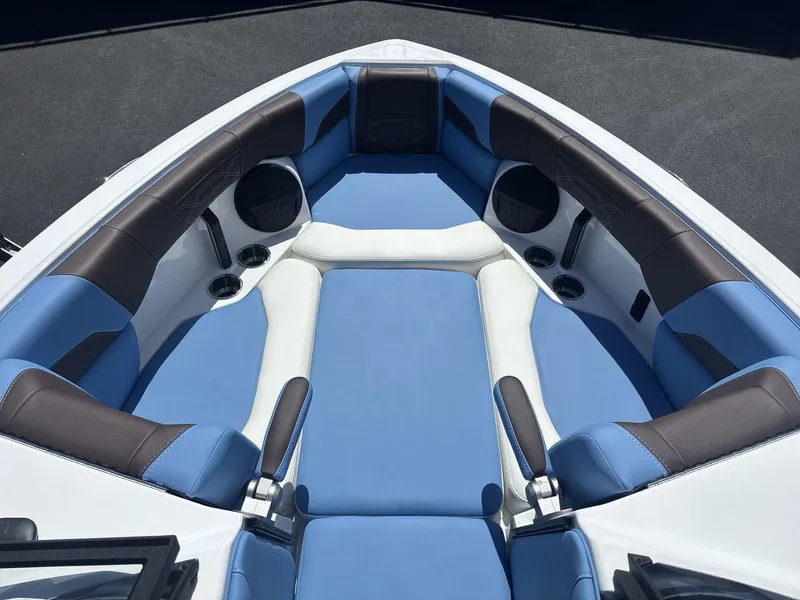 Slide: The Image of 2024 Malibu 25LSV boat interior with blue and brown seating, cup holders, and speakers. - 7