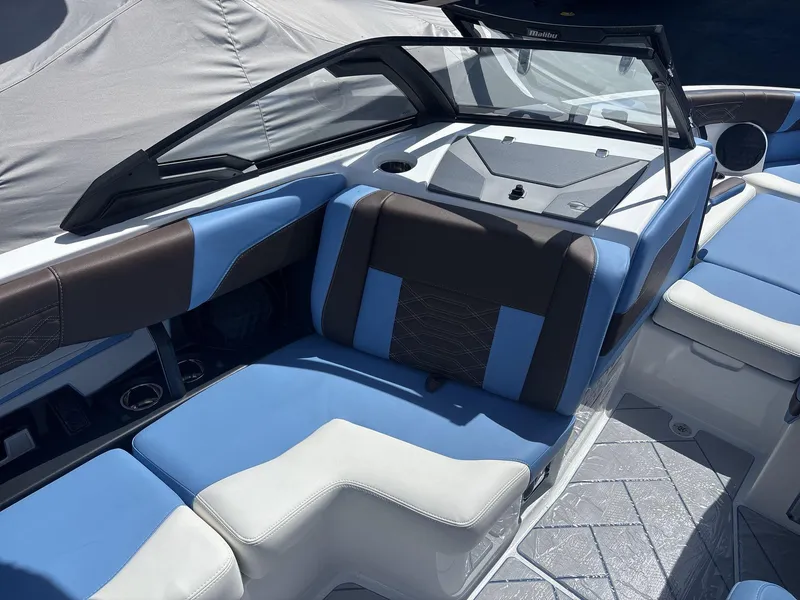 Slide: The Image of 2024 Malibu 25LSV boat interior with blue and brown seating, modern design. - 9
