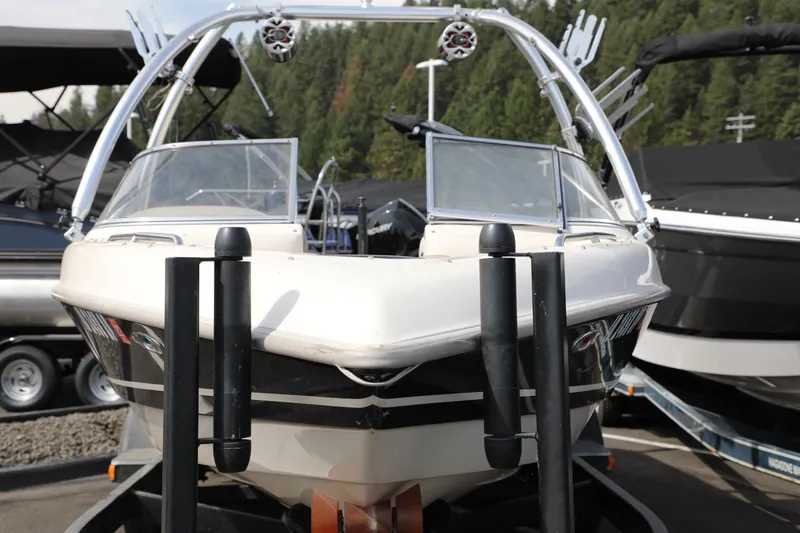 Slide: The Image of 2000 Tigé 2100V boat on trailer, parked outdoors, surrounded by trees and other boats. - 3