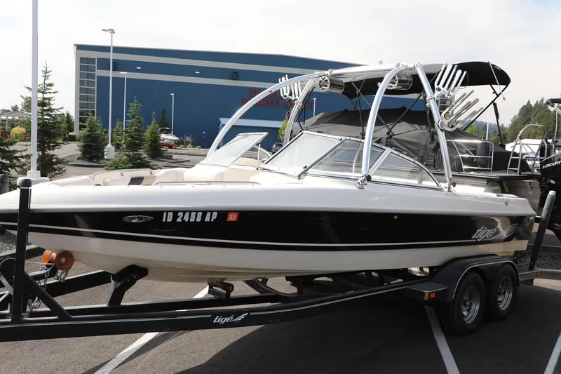 Slide: The Image of 2000 Tigé 2100V boat on trailer, parked outdoors near a blue building. - 4