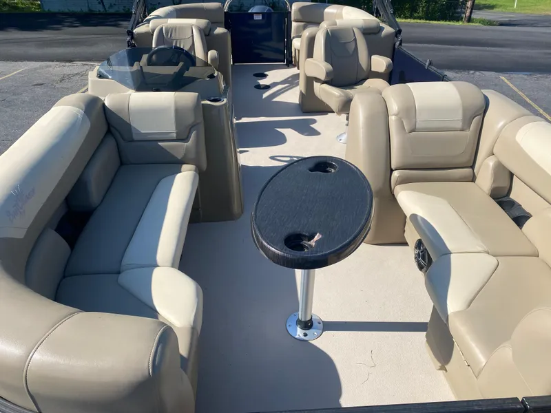Slide: The Image of 2022 SunChaser Geneva 22 LR DH pontoon boat interior with beige seating and central table. - 10