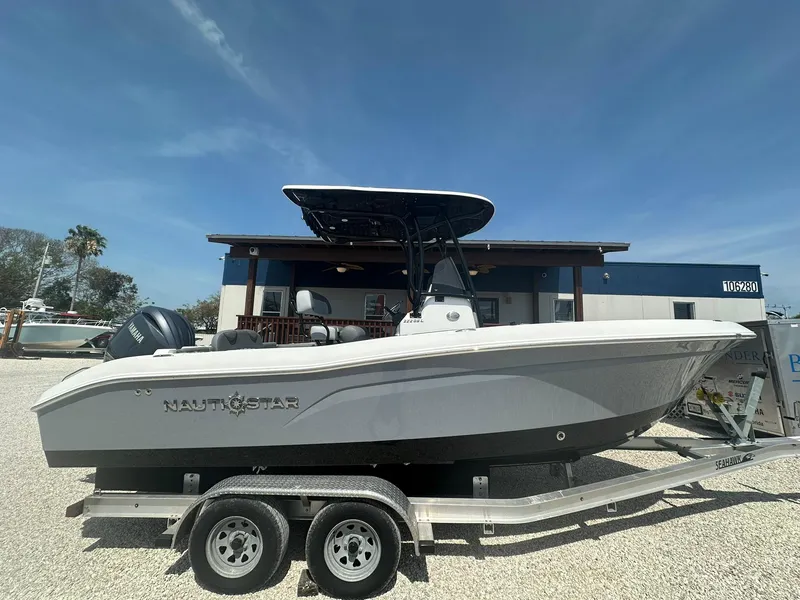 Slide: The Image of 2024 NauticStar 222 OSL boat on a trailer in a marina. - 0