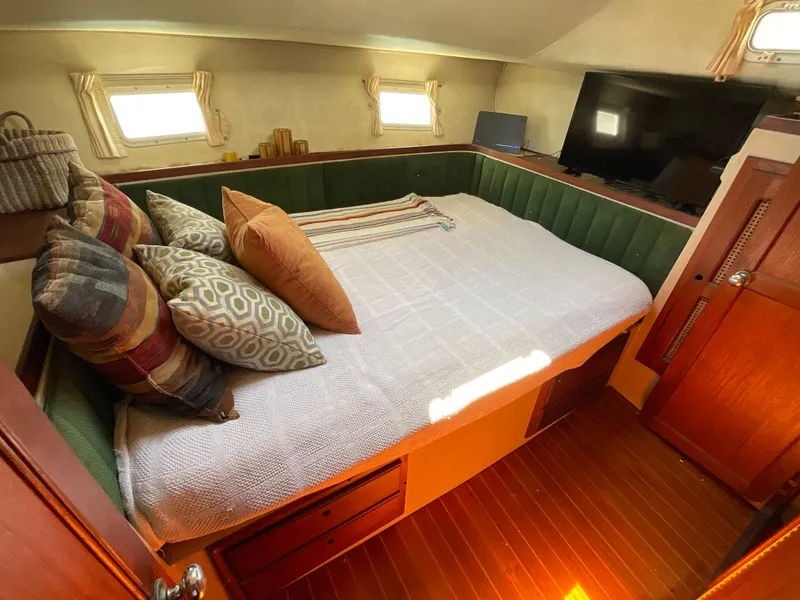 Slide: The Image of Cozy bedroom in 1983 Lancer 40 yacht with pillows, TV, and wooden accents. - 10