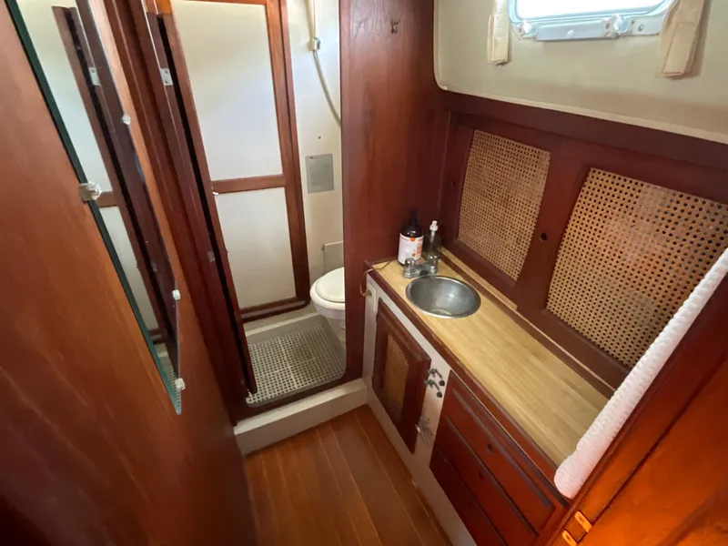 Slide: The Image of 1983 Lancer 40 yacht bathroom with wooden cabinetry, sink, and shower area. - 11