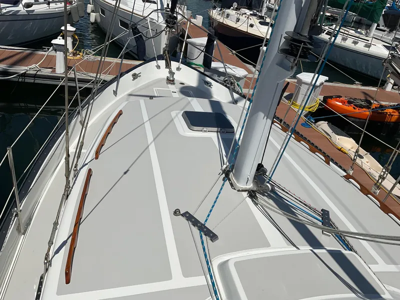 Slide: The Image of 1983 Lancer 40 sailboat deck view at marina, showcasing rigging and docked boats. - 12
