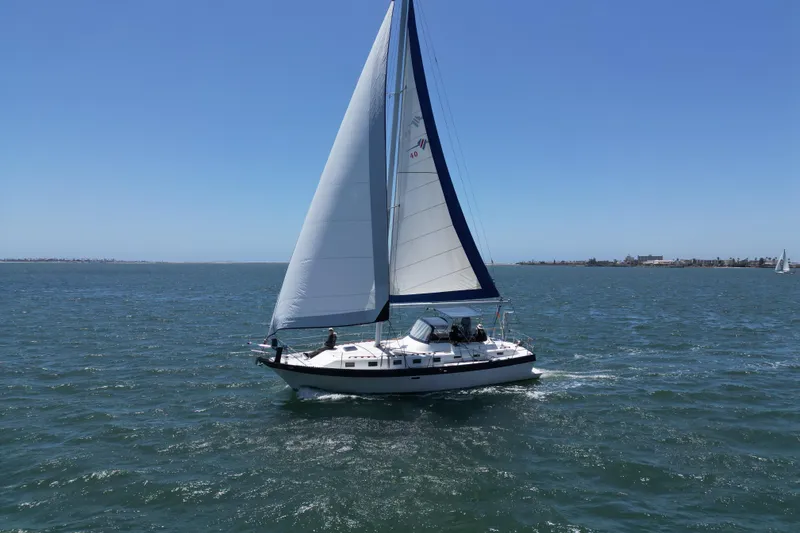 Slide: The Image of 1983 Lancer 40 sailboat cruising on open water under clear blue skies. - 2