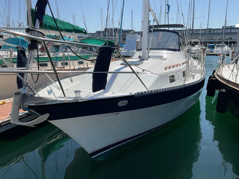 Slide: The Image of 1983 Lancer 40 sailboat docked in marina, featuring sleek white hull and blue trim. - 4