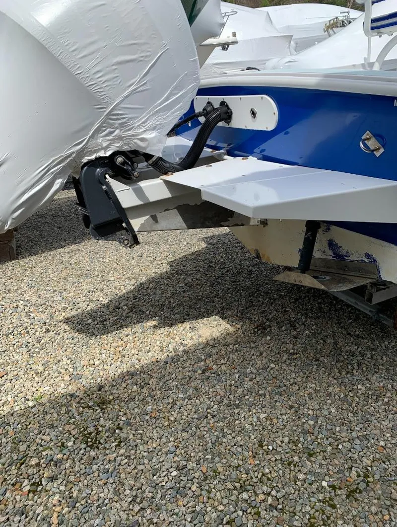 Slide: The Image of 1980 Mako 23 boat rear view on gravel, showing motor mount and blue hull. - 15