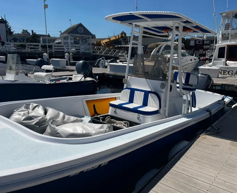 Slide: The Image of 1980 Mako 23 boat docked, featuring blue and white seating, with a T-top canopy. - 7