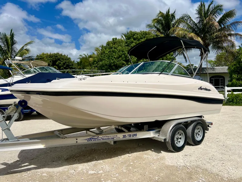 Slide: The Image of 2002 Hurricane 194 boat on a trailer with a black canopy, parked outdoors. - 3