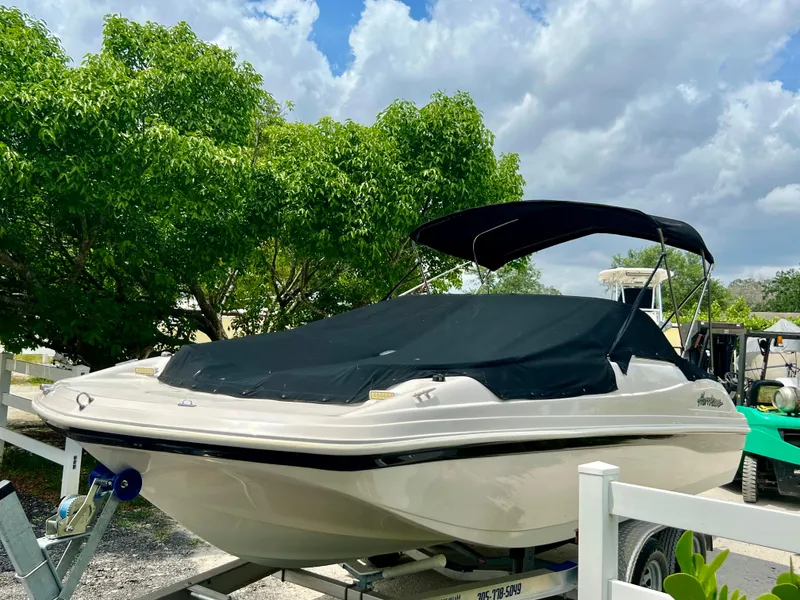 Slide: The Image of 2002 Hurricane 194 boat with black cover on trailer, parked outdoors. - 35
