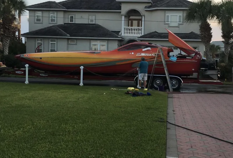 The Image of 2007 Eliminator 36 Daytona Coupe speedboat on trailer in front of a house. - 1