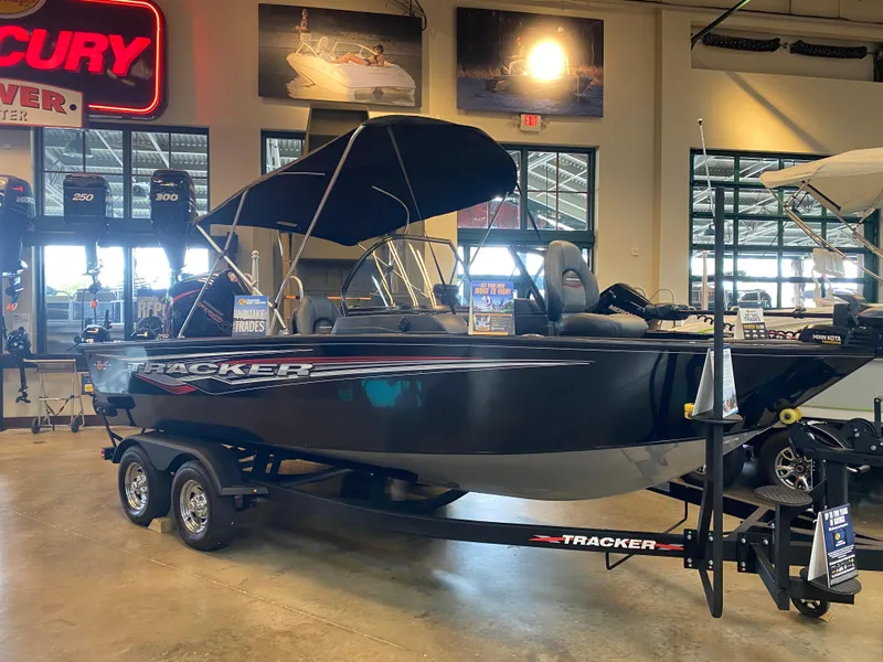 Slide: The Image of 2024 Tracker Targa V-18 Combo boat displayed indoors with canopy and trailer. - 15