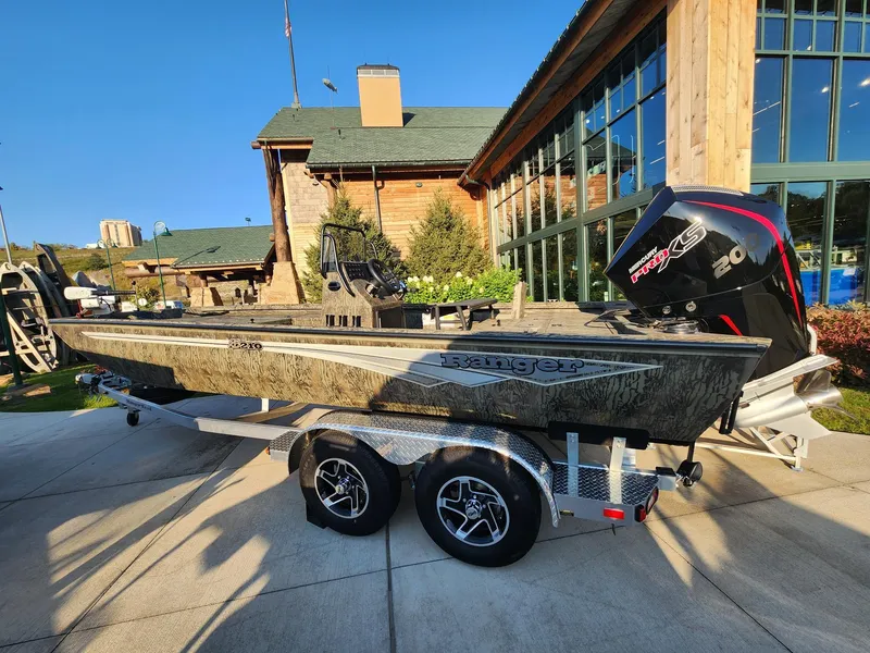 The Image of 2024 Ranger RB210 boat on trailer, parked outside rustic building. - 0