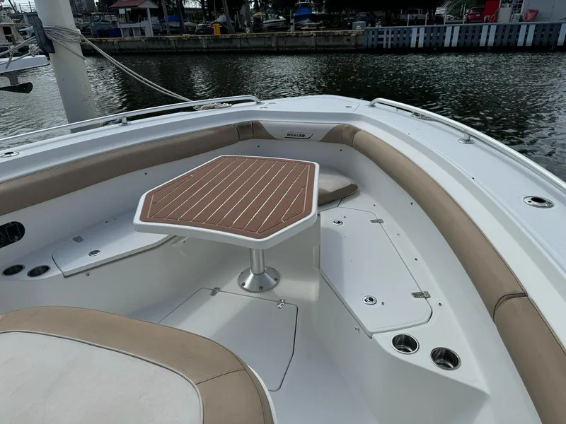 Slide: The Image of Boston Whaler 370 Outrage 2010 boat interior with seating and table, docked by the water. - 2