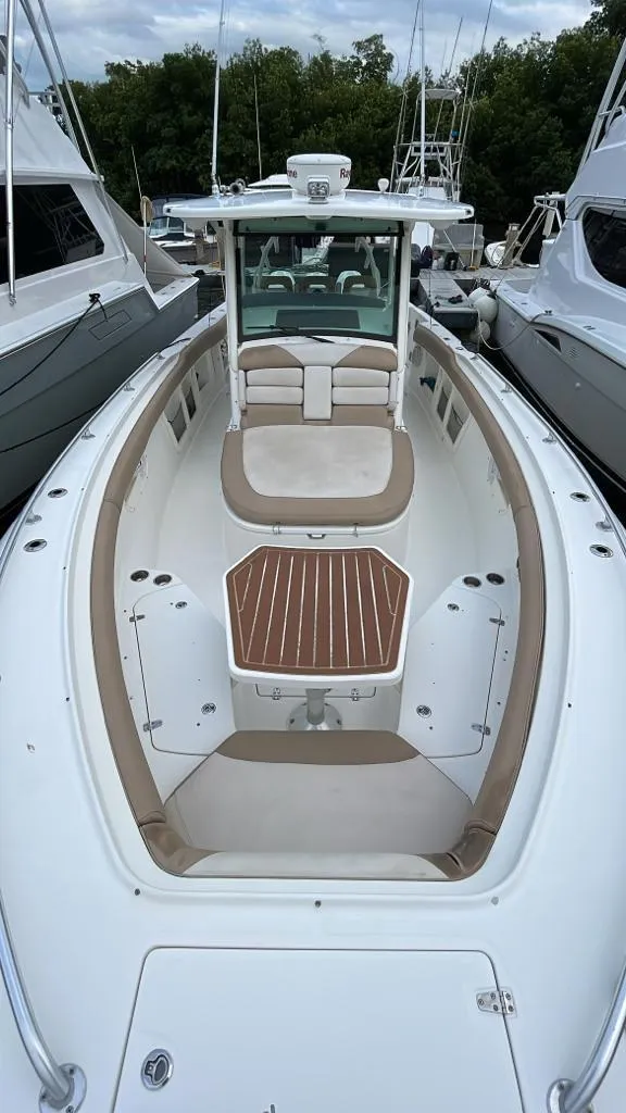 Slide: The Image of 2010 Boston Whaler 370 Outrage boat with spacious deck and seating, docked between yachts. - 3