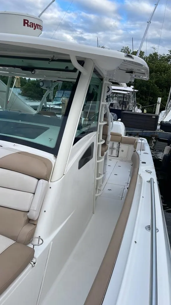 Slide: The Image of 2010 Boston Whaler 370 Outrage boat with beige seating and white exterior, docked at marina. - 4