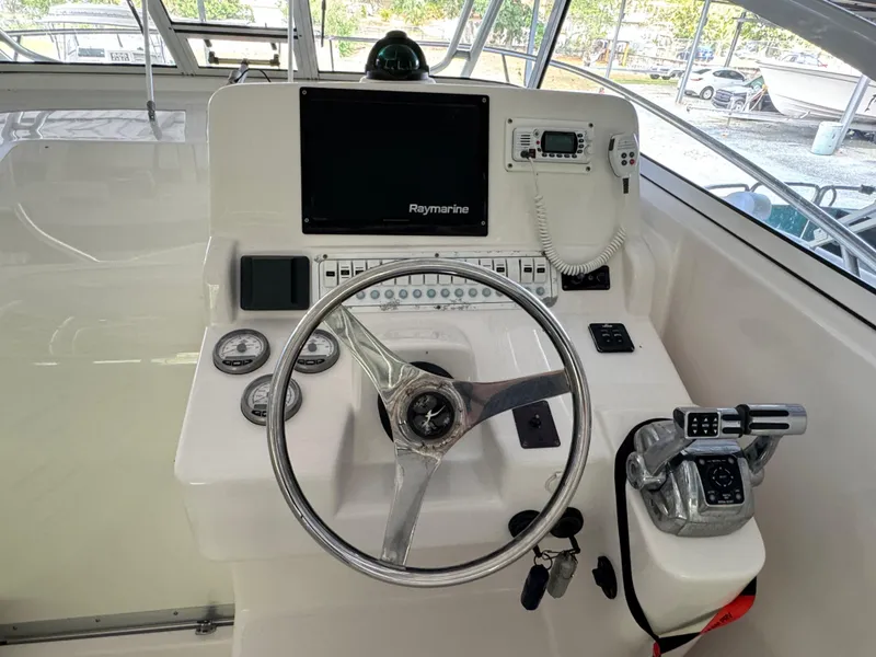 Slide: The Image of 2005 Pro-Line 32 Express helm with steering wheel, Raymarine display, and control panel. - 2