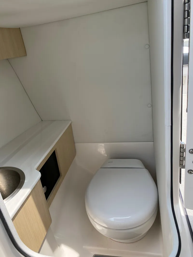 Slide: The Image of 2025 Regal LX4 boat bathroom with modern sink, toilet, and wooden cabinetry. - 10