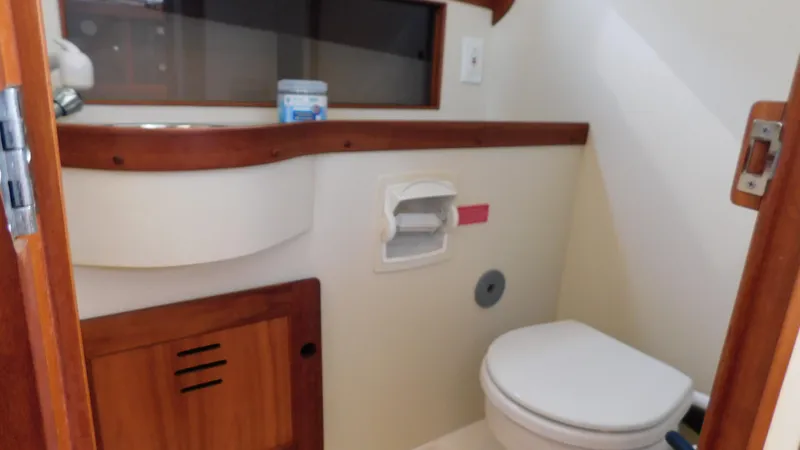 Slide: The Image of 2005 Legacy Yachts 28 Express bathroom with wooden cabinetry and white fixtures. - 13