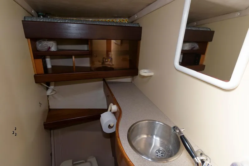 Slide: The Image of Compact bathroom in a 1985 Beneteau 42 First sailboat with sink and storage shelves. - 13