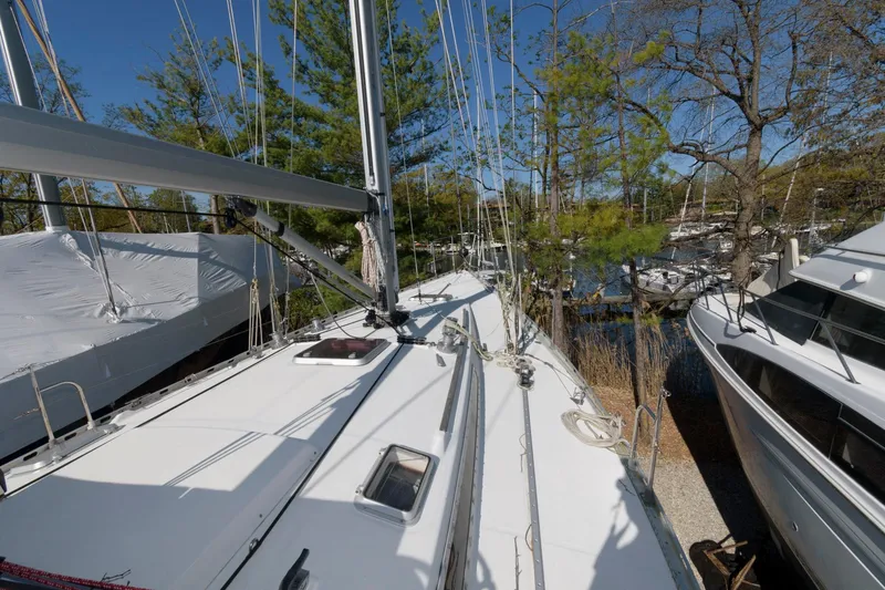 Slide: The Image of 1985 Beneteau 42 First sailboat on dry dock, surrounded by trees and other boats. - 14