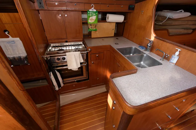 Slide: The Image of 1985 Beneteau 42 First yacht kitchen with wooden cabinetry, stove, and double sink. - 5