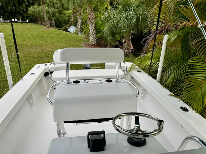 Slide: The Image of 2024 Rambo 22 Center Console boat interior with steering wheel and seating, surrounded by lush greenery. - 15