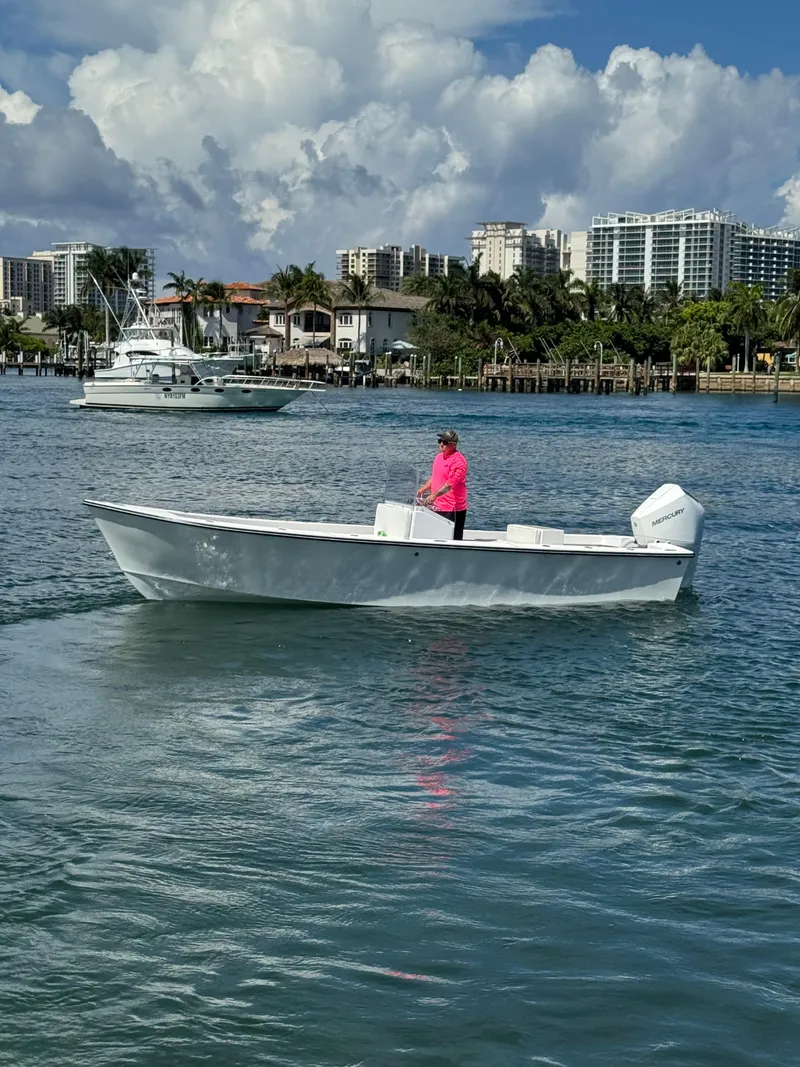 Slide: The Image of 2025 Rambo 22 Center Console boat on water, with person in pink shirt steering. - 2
