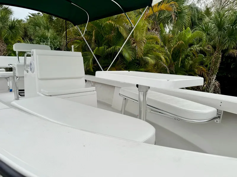 Slide: The Image of 2024 Rambo 22 Center Console boat with white seating and table, surrounded by lush greenery. - 20