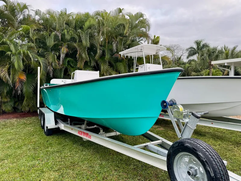 Slide: The Image of 2024 Rambo 22 Center Console boat on trailer, turquoise hull, parked on grass. - 29