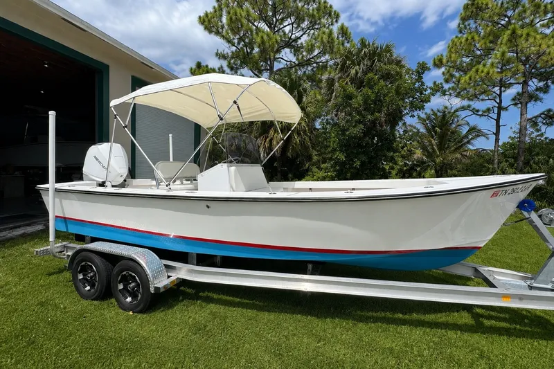 Slide: The Image of 2026 Rambo 22 Center Console boat on trailer, parked on grass, with canopy and trees in background. - 0