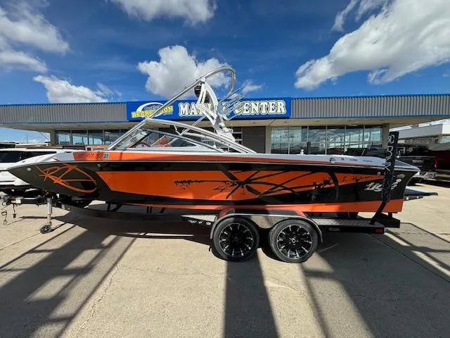 Slide: The Image of 2008 Tigé RZR 24 boat in orange and black, parked at a marine center. - 4