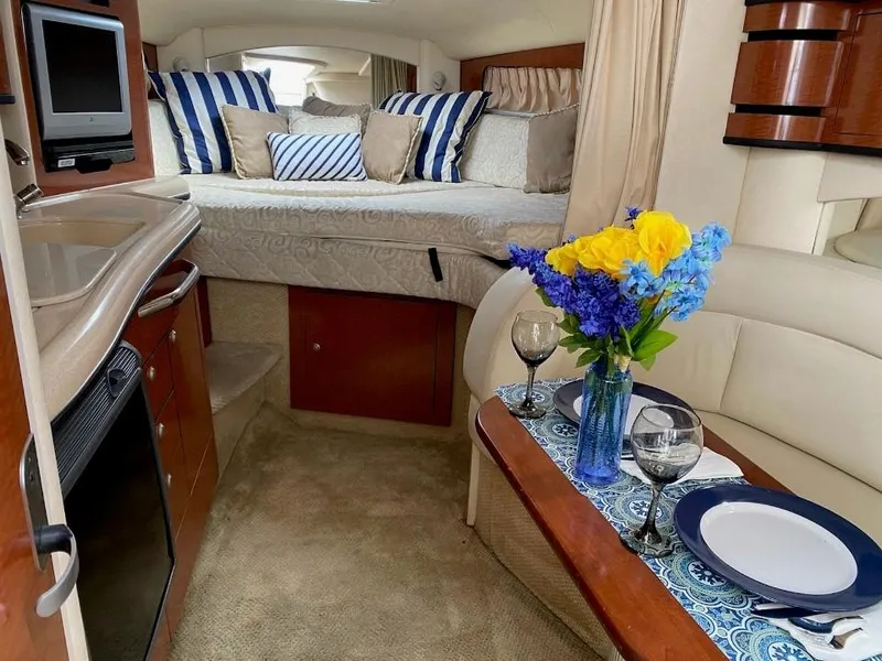 Slide: The Image of Interior of 2005 Sea Ray SUNDANCER 300 with cozy bed, dining area, and kitchenette. - 3