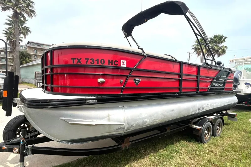 Slide: The Image of 2019 Trifecta 23C 3.0 pontoon boat on trailer, red and black exterior. - 2