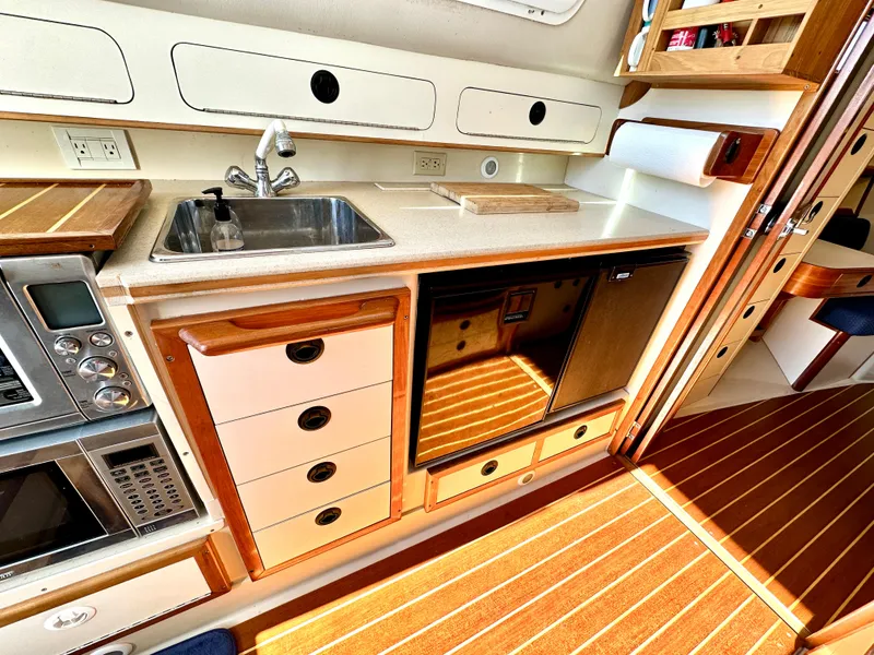 Slide: The Image of 2004 Albin 35 Command Bridge galley with sink, microwave, and wooden cabinetry. - 37