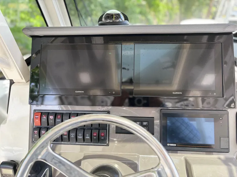 Slide: The Image of 2022 Pursuit S 288 boat dashboard with Garmin displays and control switches. - 10