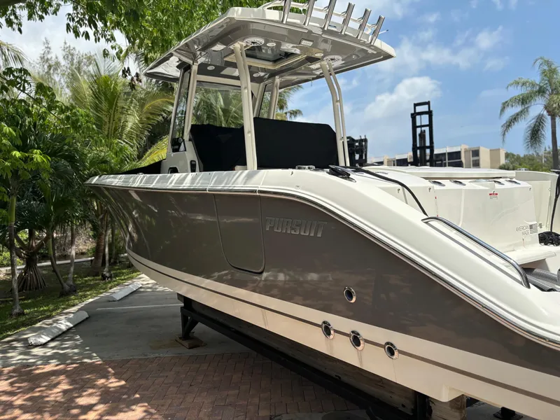 Slide: The Image of 2022 Pursuit S 288 boat on a trailer, surrounded by palm trees. - 4