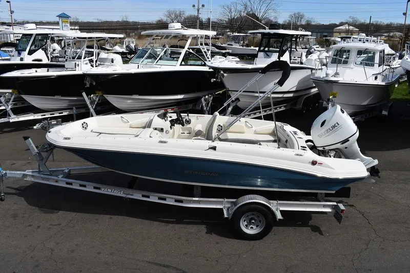 The Image of 2024 Stingray 182SC boat on trailer at marina, surrounded by other boats. - 0
