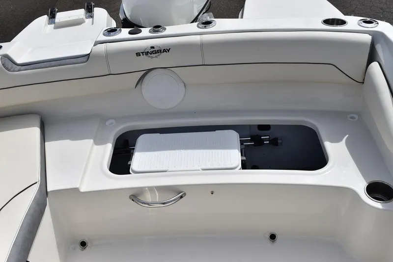 Slide: The Image of 2024 Stingray 182SC boat interior storage compartment with white cushioned seating. - 18