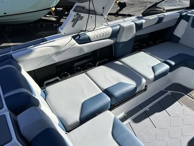 Slide: The Image of 2024 Malibu M220 boat interior with blue and white cushioned seating. - 11